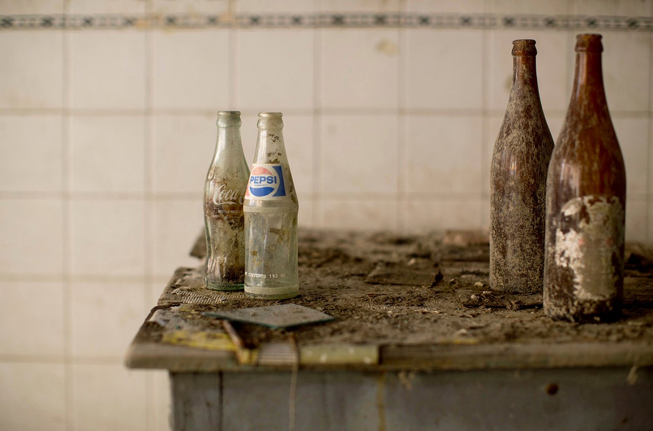 Coca-Cola and Pepsi bottles stand on a table at an abandoned cafe in the United Nations buffer zone in central Nicosia