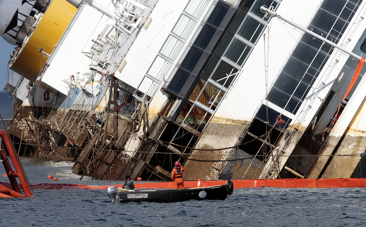 Salvage crew workers are seen in front of the capsized Costa Concordia cruise liner after the start of the 