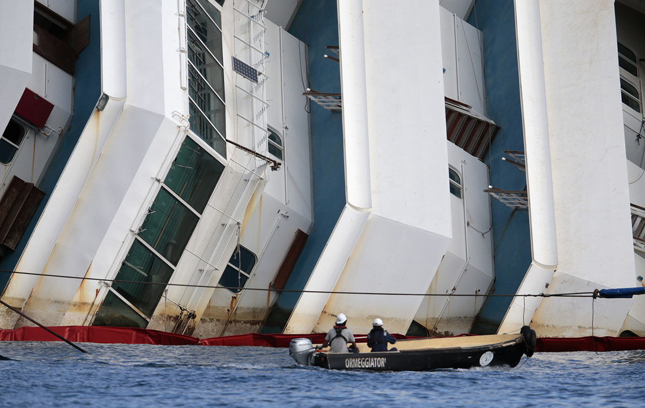 Salvage crew workers follow an operation to raise the capsized cruise liner Costa Concordia from a boat next to it, outside Giglio harbour