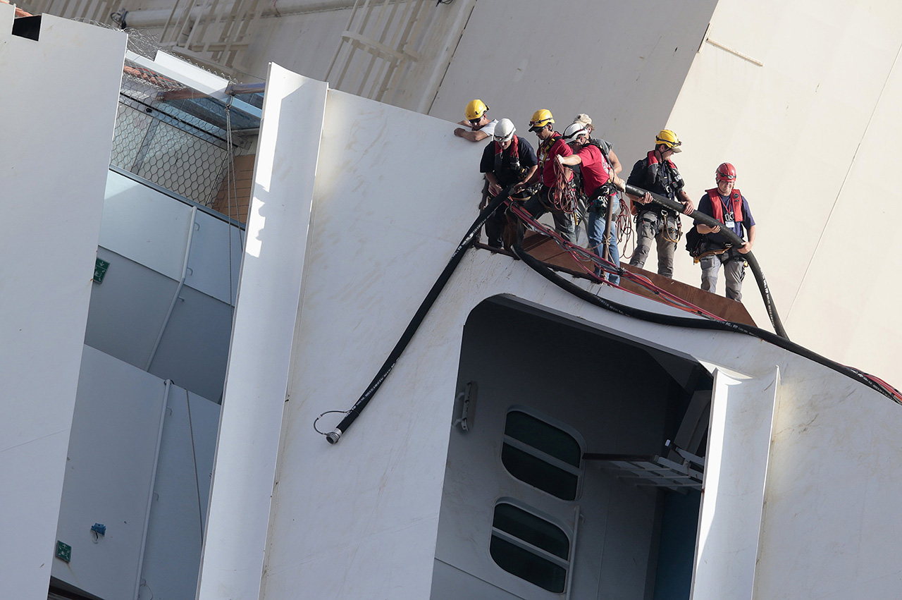 Salvage crew workers work on a side of the capsized Costa Concordia cruise liner outside Giglio harbour