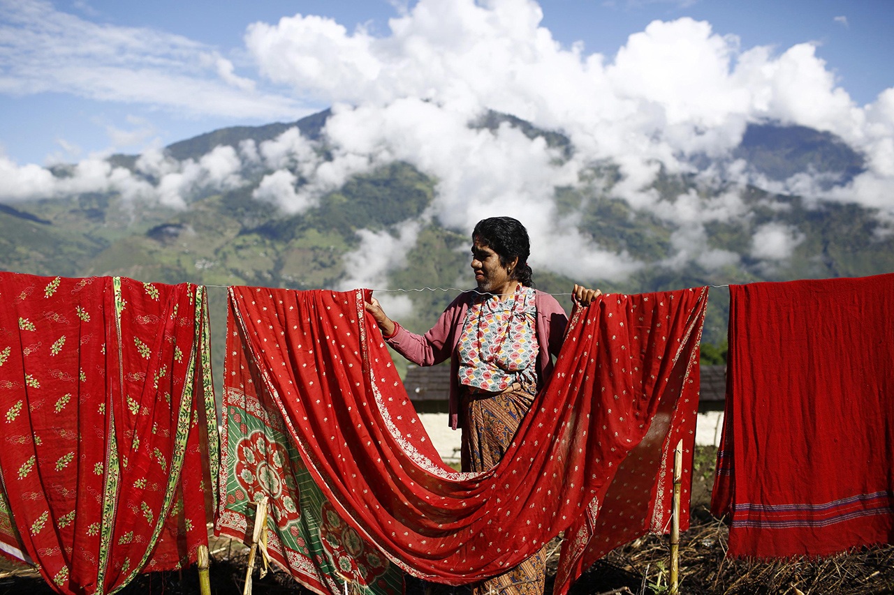 Devi Budhathoki dries her clothes outside her house in Kharay, Dolkha District