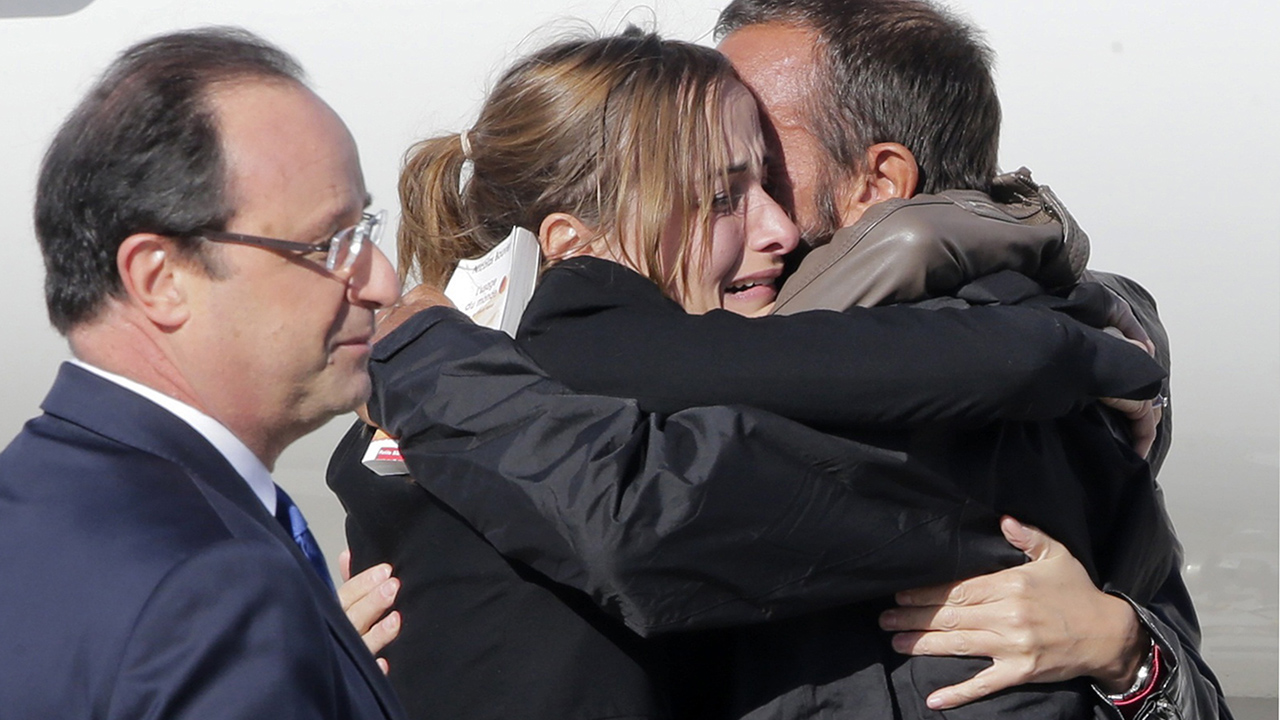 Former French hostage Larribe is welcomed by relatives next to French President Hollande upon their arrival at Villacoublay military airport, near Paris