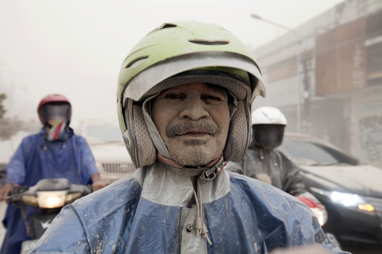 A man covered by ash from Mount Kelud as stand on his motorcycles in Yogyakarta