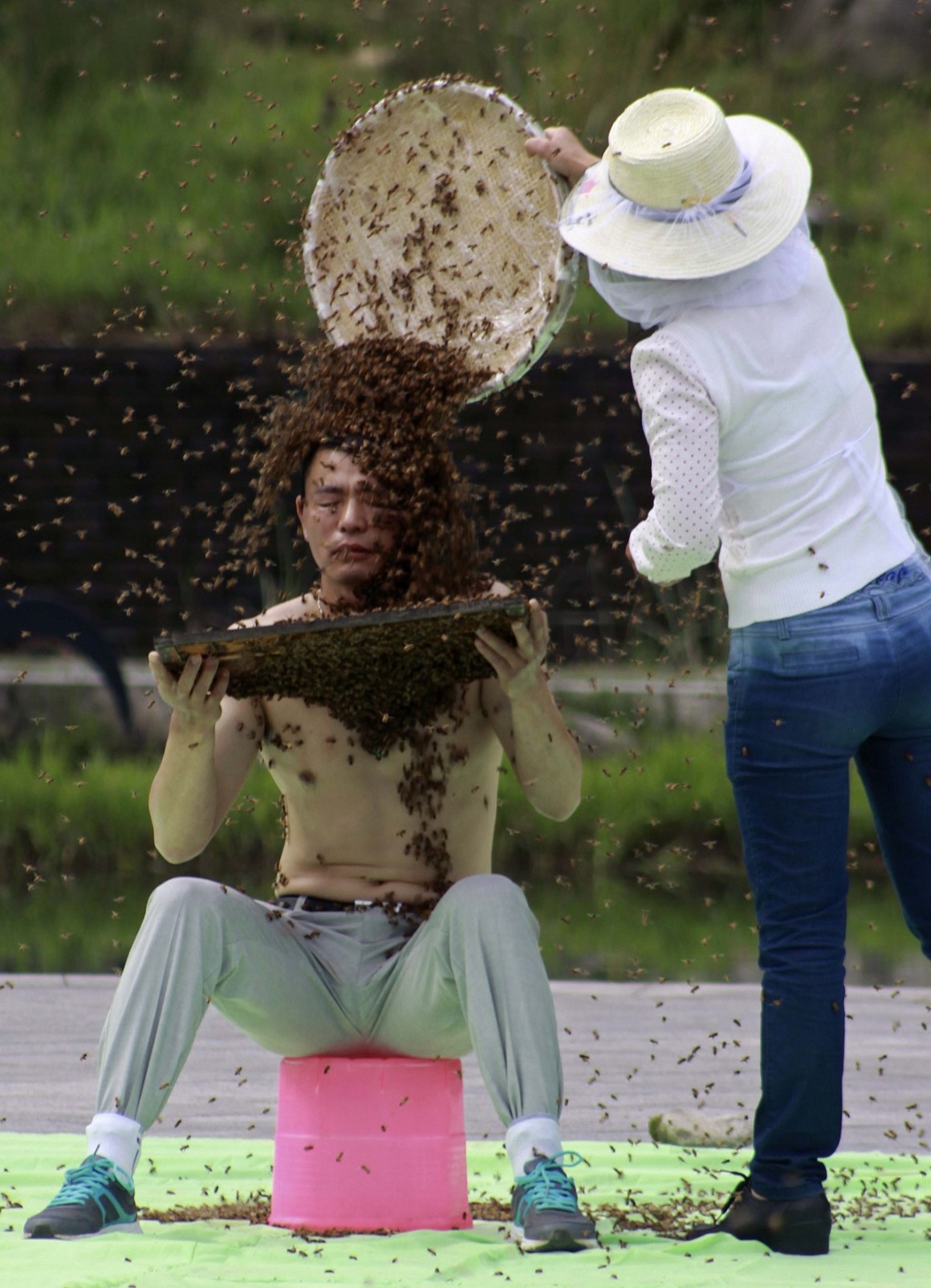 Beekeeper Ruan Liangming closes his eyes as he is covered by a swarm of bees in Yichun