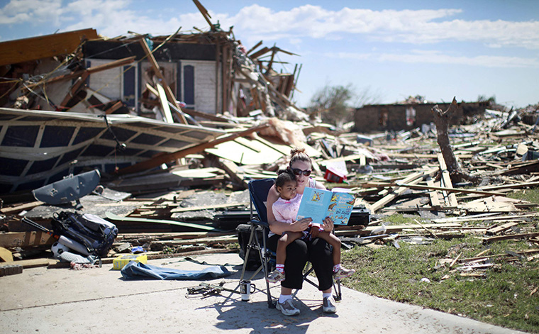 Sarah Dick reads a Doctor Seuss book to her three-year-old daughter Jadyn at the driveway of her tornado-destroyed house in Oklahoma City