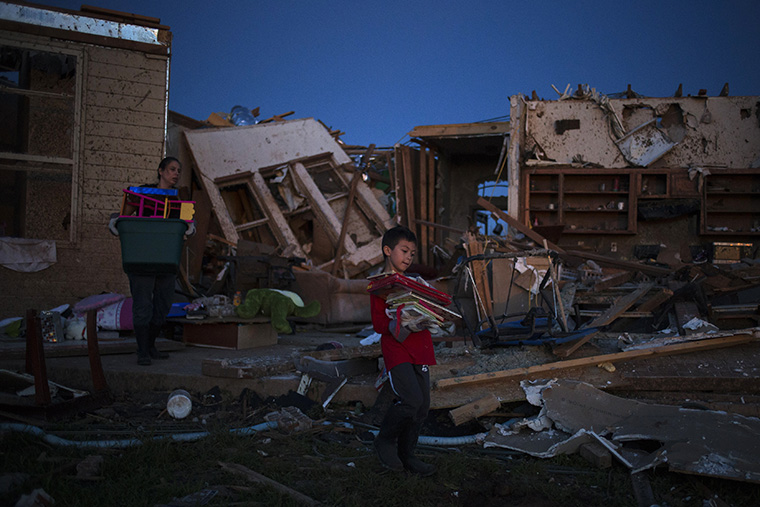 Ethan carries books he recovered from his damaged house in Moore, Oklahoma, two days after the Oklahoma City suburb was left devastated by a tornado