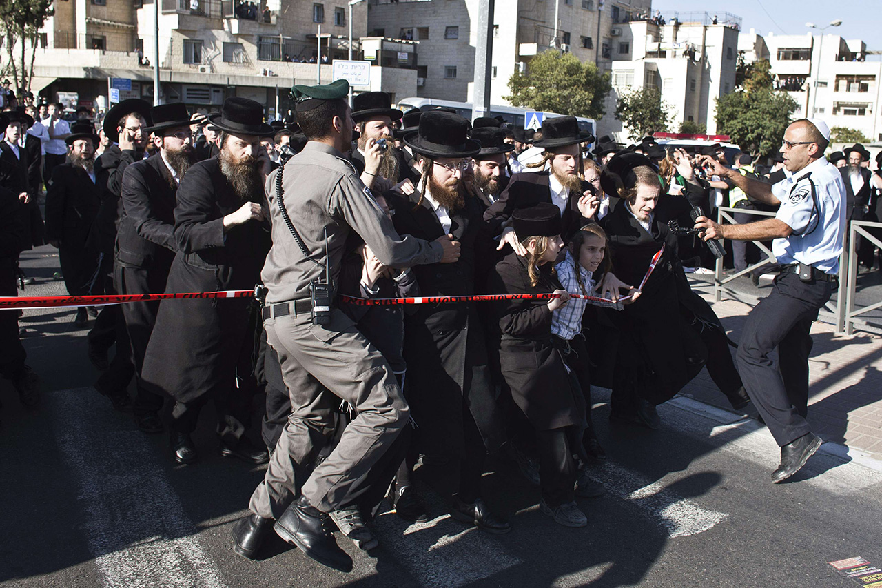 Ultra-Orthodox Jewish men try to push past a police cordon in an attempt to reach a vehicle transporting the body of Rabbi Yosef before his funeral in Jerusalem